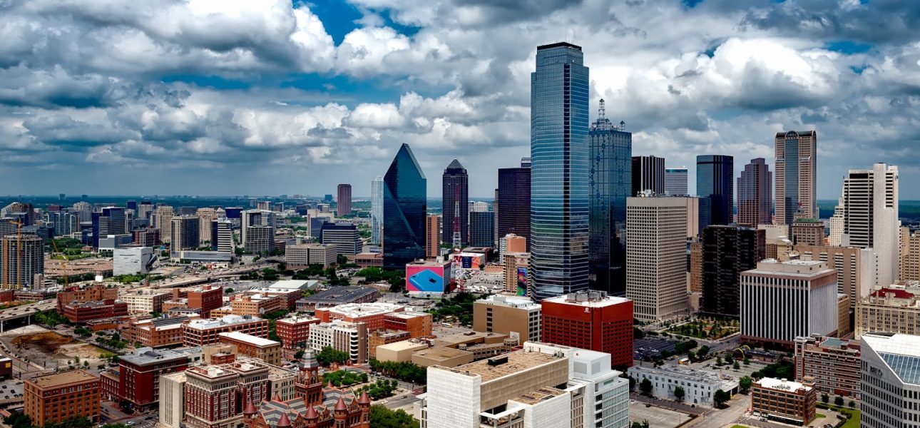 A stunning panoramic view of the Dallas skyline under dramatic clouds, capturing the city's iconic skyscrapers.
