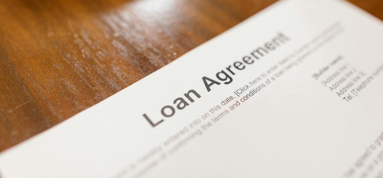 Detailed loan agreement document close-up on a wooden table representing legal and financial concepts.