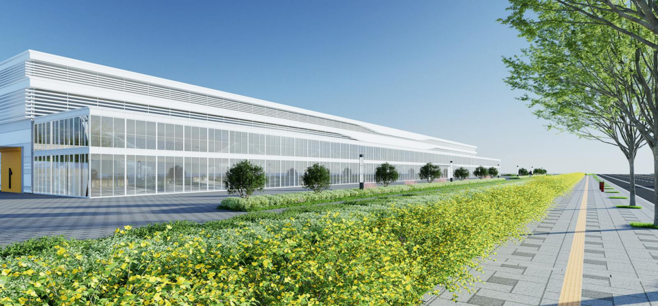 Contemporary industrial building exterior with a landscaped walkway, bright sky, and greenery.