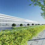 Contemporary industrial building exterior with a landscaped walkway, bright sky, and greenery.