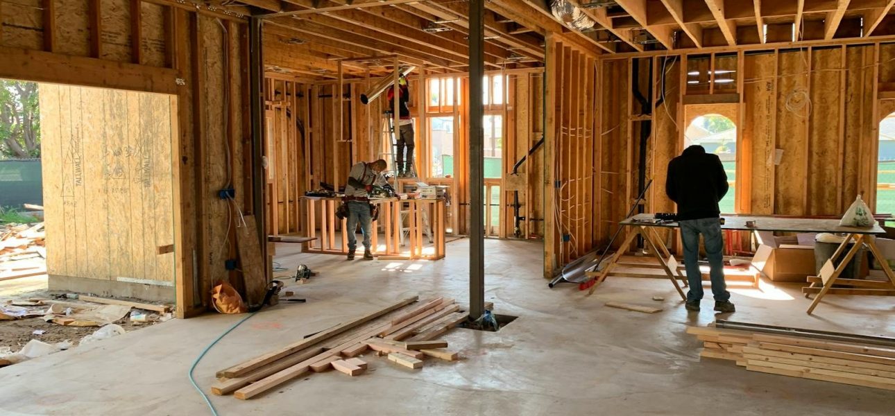 Workers constructing a house framework, showcasing interior carpentry and building process.