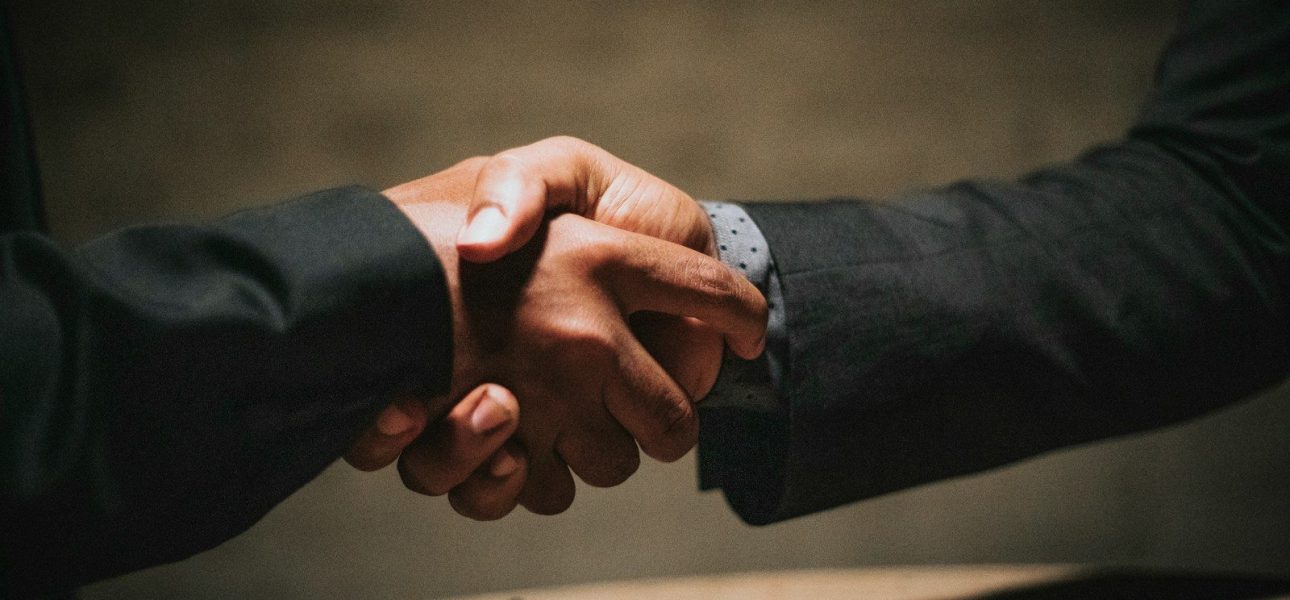two people shaking hands over a wooden table