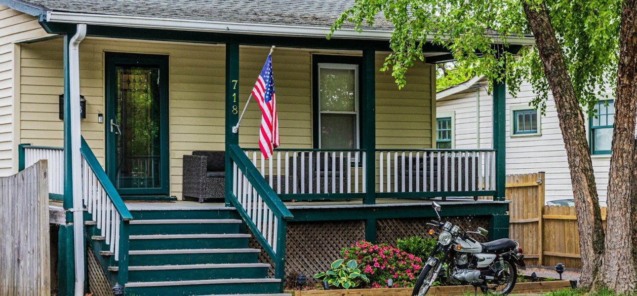 A modest house with a porch and a motorcycle.