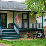 A modest house with a porch and a motorcycle.