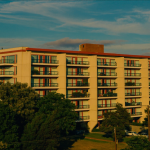 Full-color photo of a modern American mid-rise apartment building at golden hour, representing multifamily bridge financing