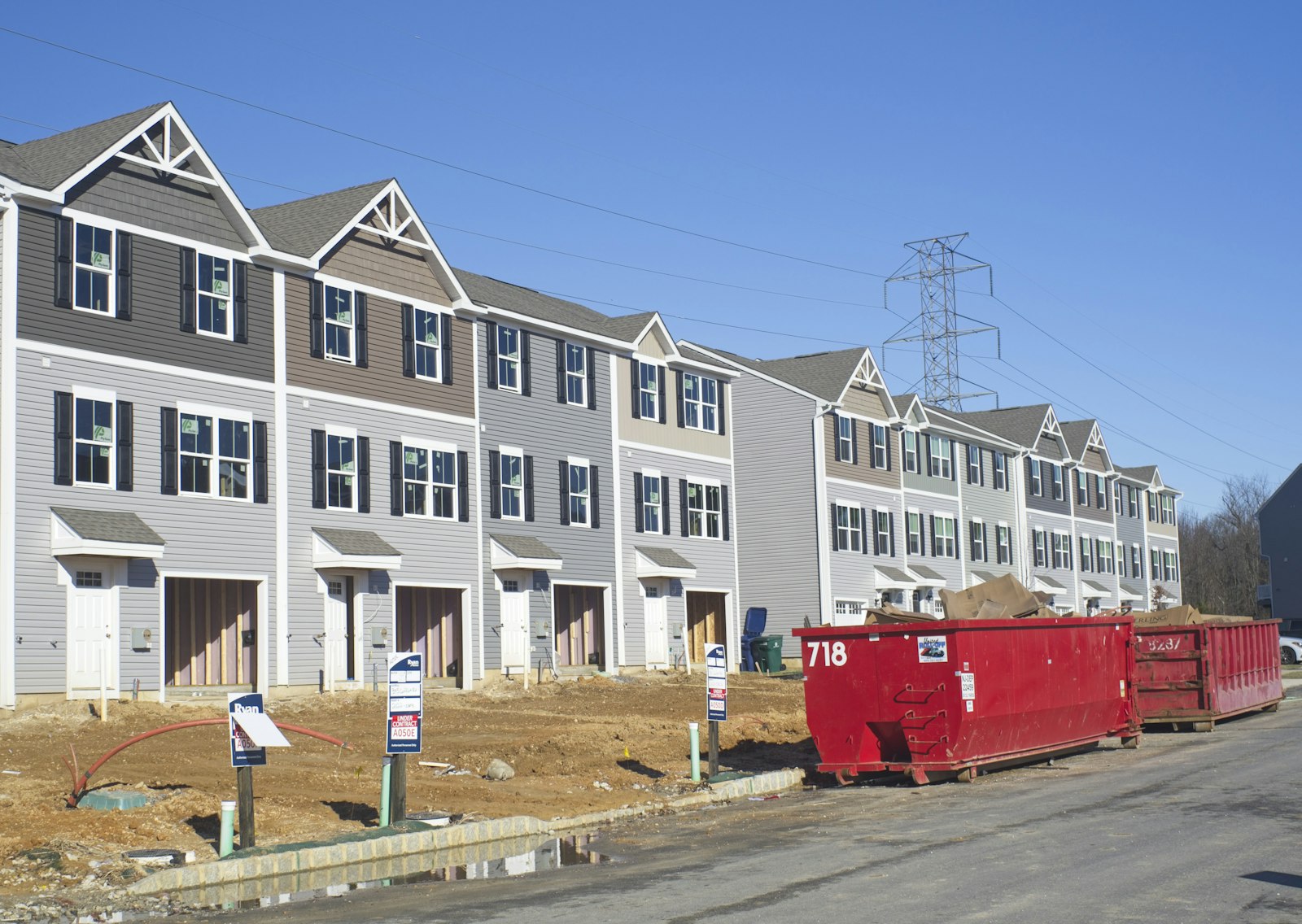 A row of townhomes under construction with a dumpster and framing materials on site