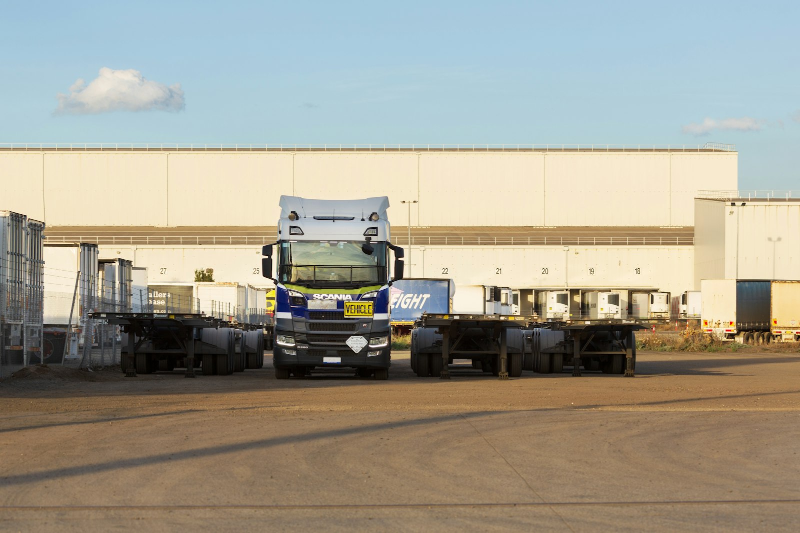 Semi trucks and trailers parked outside a distribution warehouse