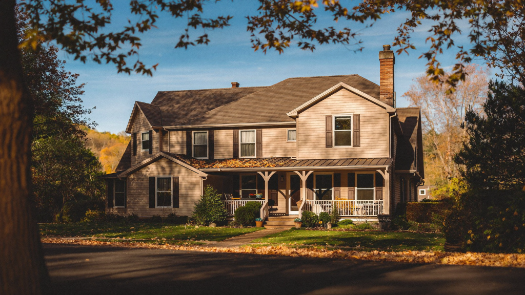 Single-family rental home with a wraparound porch on a tree-lined street in Louisville, Kentucky in autumn