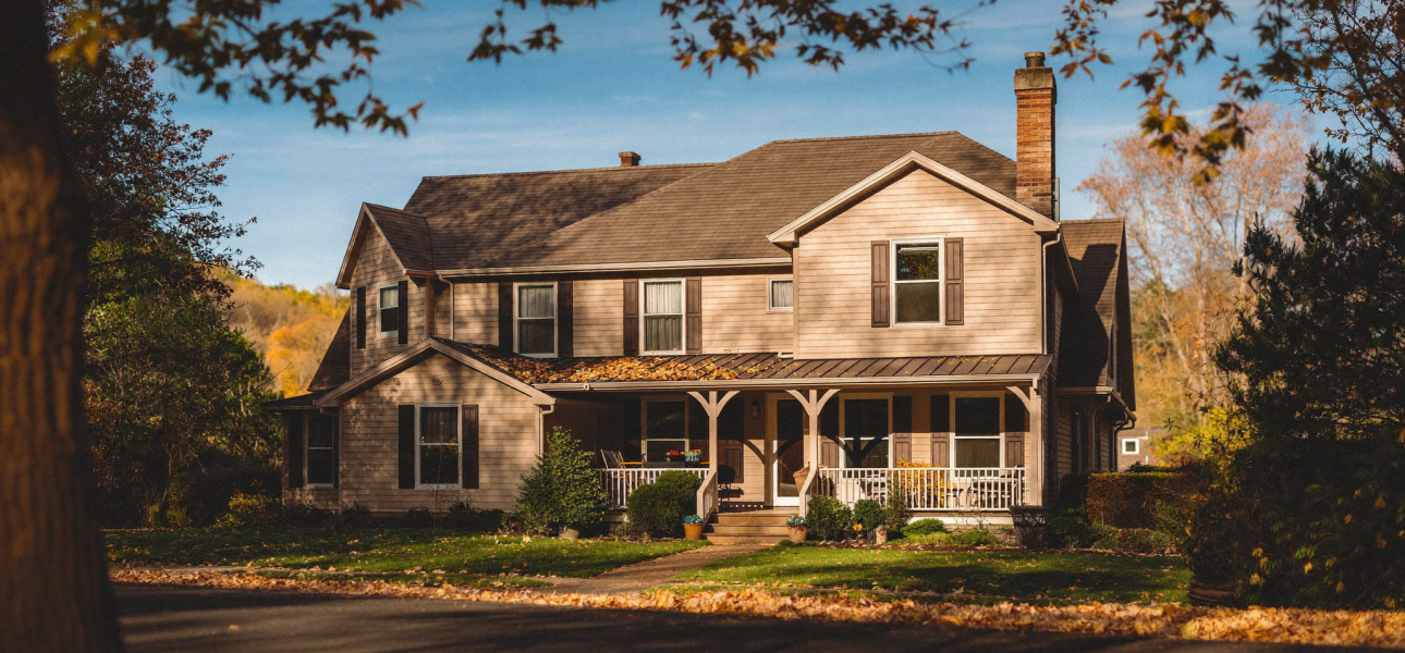 Single-family rental home with a wraparound porch on a tree-lined street in Louisville, Kentucky in autumn