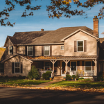 Single-family rental home with a wraparound porch on a tree-lined street in Louisville, Kentucky in autumn