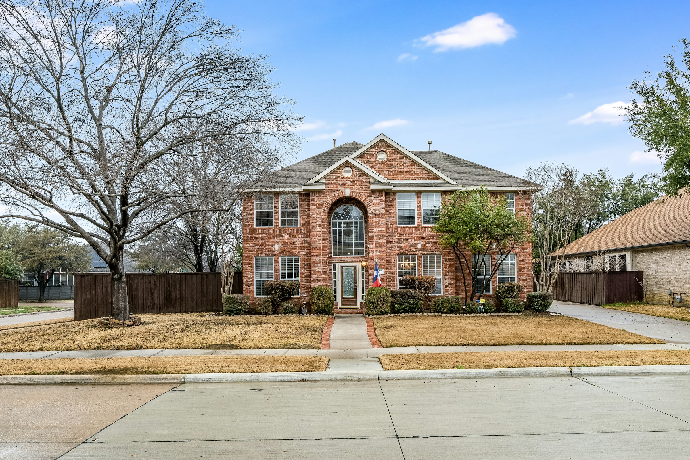 Renovated two-story brick single-family home on a Texas suburban street in daylight