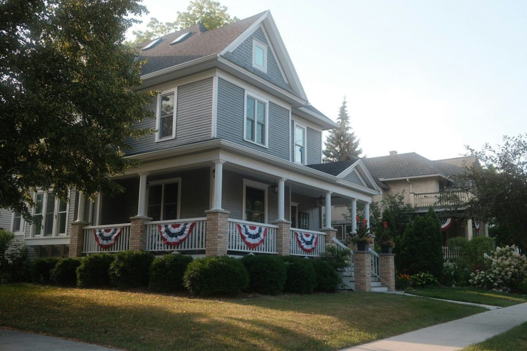Two-story American house with front porch and flag bunting