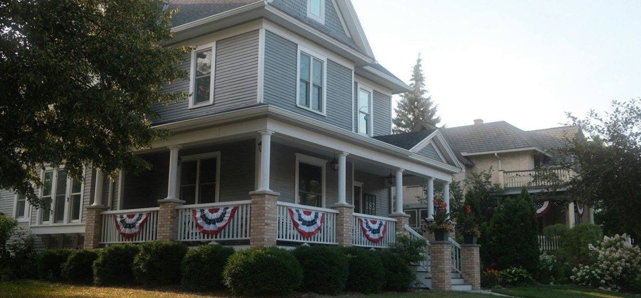 Two-story American house with front porch and flag bunting