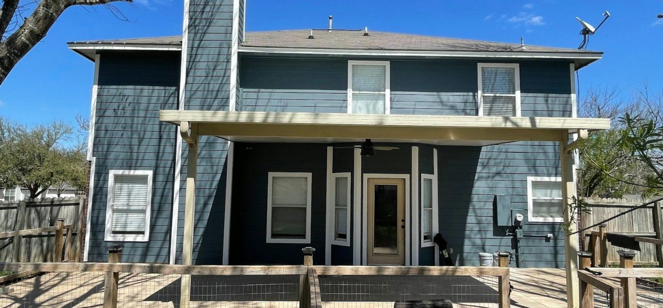 Two-story blue house with deck in Central Texas